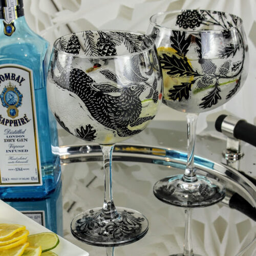 Bombay sapphire london dry gin pair of gin and tonic glasses with dancing hares in a oak forest
